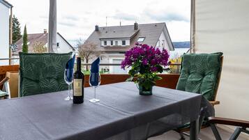 A table set outdoors with a tablecloth, two wine glasses, and a bottle of wine.