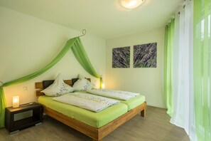 A double bed with a canopy, bedside lamps, a nightstand, and two wall-mounted paintings. - Cozy, Lovingly Furnished Holiday Apartment "Lavendel" with Covered Terrace & Balcony (Sipplingen am Bodensee)