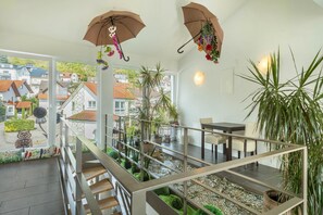 Un intérieur moderne avec un escalier, des plantes d’intérieur et une vue sur l’extérieur.