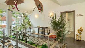 Un interior moderno con una escalera, plantas en macetas y paraguas colgando.