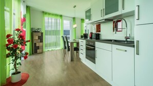 A modern kitchen with white cabinets, a built-in oven, and a dining area with a table and chairs. - Apartment "Rose" with Large Balcony and Stunning Lake, Forest, and Mountain Views (Sipplingen am Bodensee)