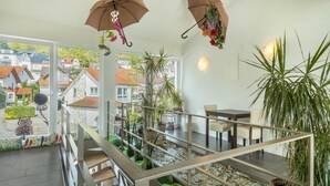 A modern interior with a staircase, indoor plants, and a view of the outside. - Apartment "Rose" with Large Balcony and Stunning Lake, Forest, and Mountain Views (Sipplingen am Bodensee)