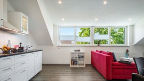 A modern apartment with a kitchen, a red sofa, and a bookshelf.