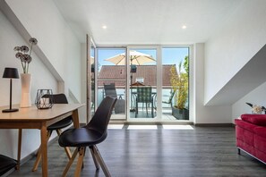 A modern interior with a dining area, a red sofa, and a view of the outside.