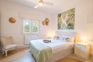 A bedroom with a bed, nightstand, chair, and a window.