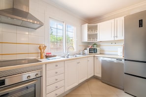 A modern kitchen with white cabinetry, stainless steel appliances, and a window providing natural light.
