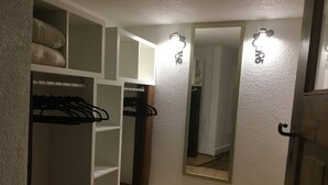 A walk-in closet with hanging space and shelves, a mirror with lights, and a tiled floor. - Beim Schloß Michel (Lauda)