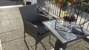 An outdoor seating area with wicker chairs and a table, surrounded by a metal railing. - Beim Schloß Michel (Lauda)