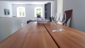 A wooden dining table with a white bowl and two wine glasses. There are two windows with greenery visible outside. - Ferienwohnungen Mittermurnthal (Neunburg vorm Wald)