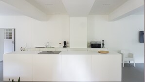 A modern kitchen with a central island, white cabinetry, and a flat-screen TV mounted on the wall. - Ferienwohnungen Mittermurnthal (Neunburg vorm Wald)