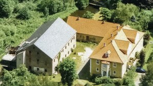 A large, historic building with multiple wings and a central courtyard, surrounded by lush greenery. - Ferienwohnungen Mittermurnthal (Neunburg vorm Wald)