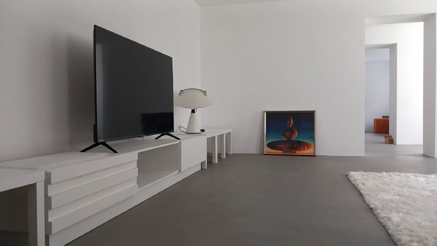 A modern living room with a large flat-screen TV, a white console table, a floor lamp, and a painting on the wall. - Ferienwohnungen Mittermurnthal (Neunburg vorm Wald)