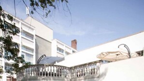 A modern building with a white exterior, a balcony with a table and chairs, and a garden with purple flowers. - Residenz Am Malerwinkel (Bad Sassendorf)