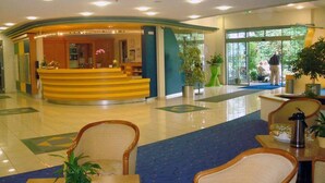 A hotel lobby with a reception desk, seating area, and large windows. - Residenz Am Malerwinkel (Bad Sassendorf)