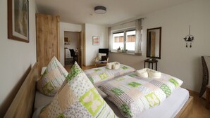 A bedroom with two beds, a wooden wardrobe, a desk, and a chair. - Ferienhof Neukirchinger (Tiefenbach)