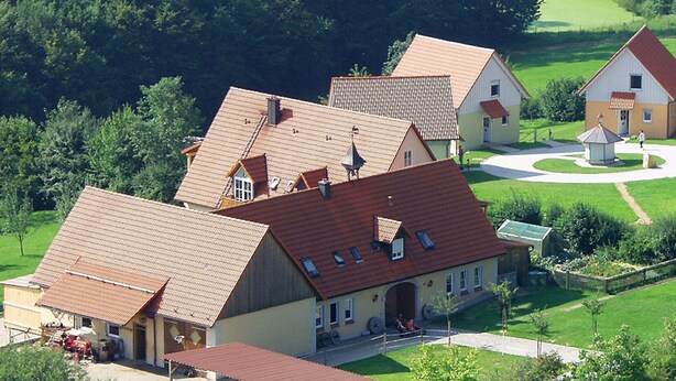 A rural setting with a large barn-like building, smaller residential houses, and a circular driveway. - Ferienanlage Karolinenhof 2 (Haundorf)