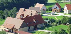 Entorn rural amb un edifici gran semblant a una era, cases residencials més petites i una calçada circular.