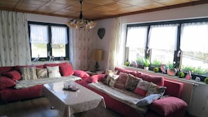 Una sala de estar acogedora con dos sofás rojos, una mesa de centro de madera y una araña.