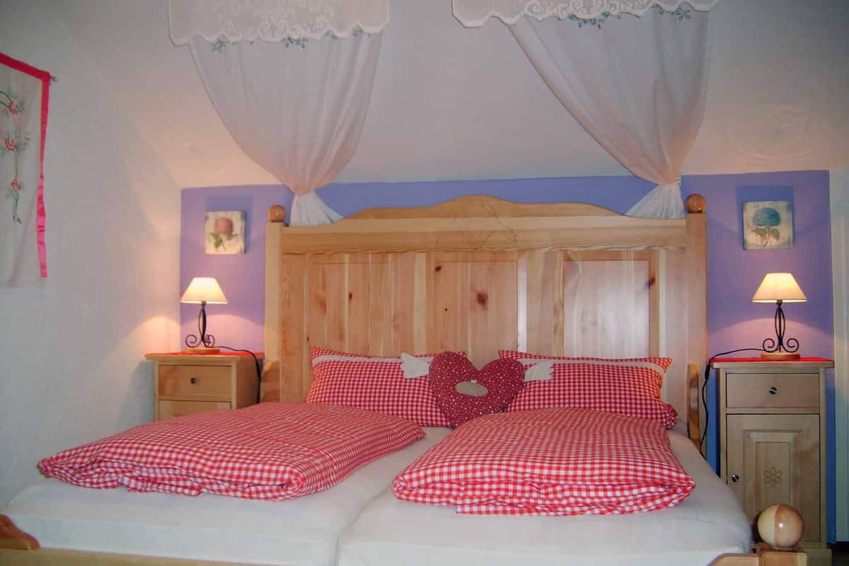 A double bed with a wooden headboard, two bedside tables with lamps, and a canopy bedspread.