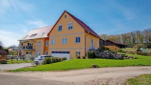 A two-story house with a sloped roof, a garage, and a stone staircase leading to the entrance. - Pferdefreunde Loberhof (Weihenzell)
