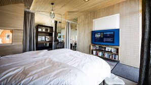 Quarto de hotel moderno com uma cama grande, televisão e estante.