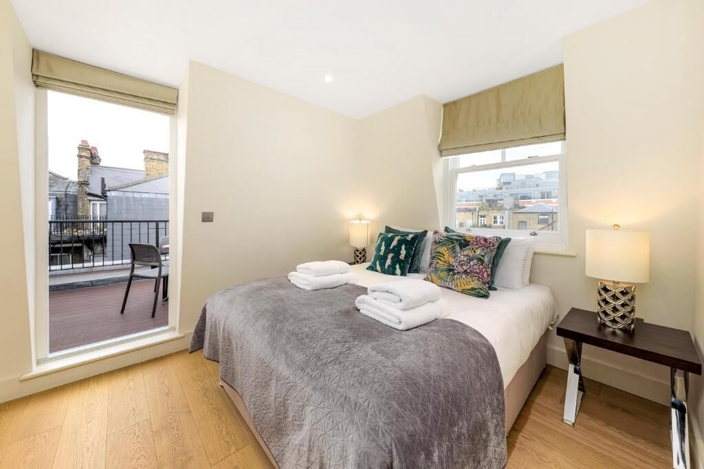 Une chambre à coucher avec un lit, deux lampes de chevet, une fenêtre donnant sur un beau paysage et un balcon avec une chaise.