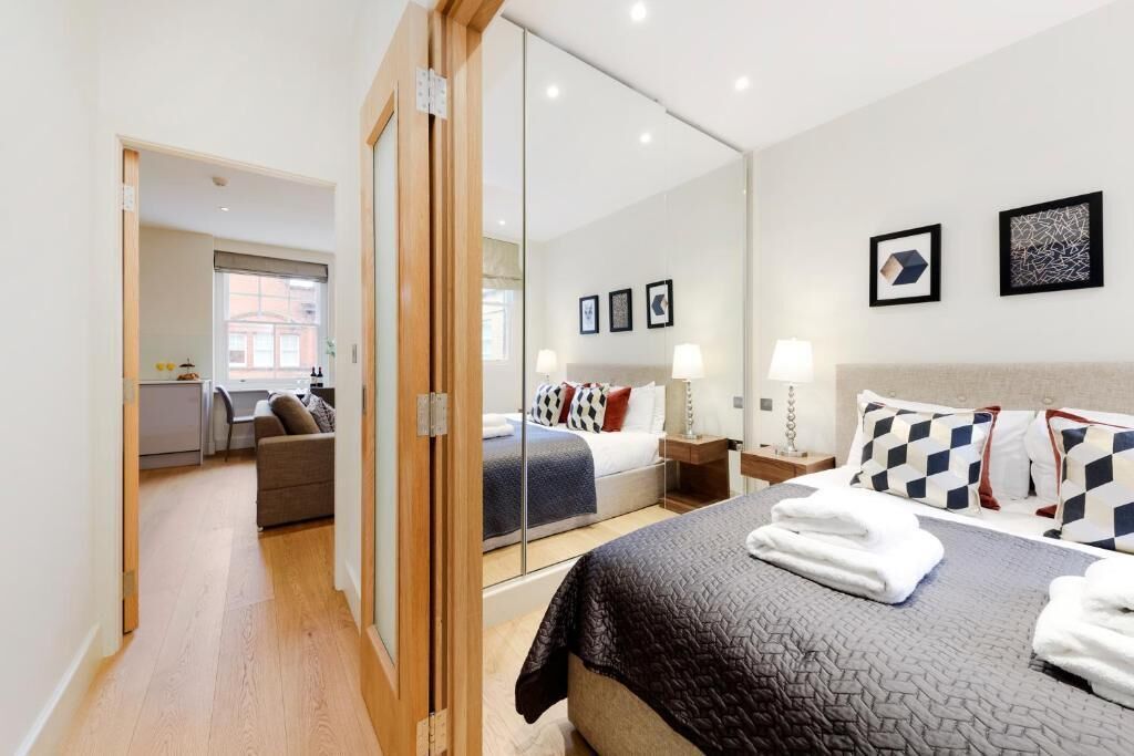 Une chambre d’hôtel avec un lit, un miroir, un bureau et une vue sur la ville.