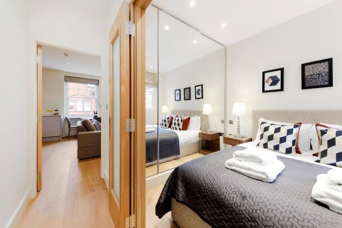 Une chambre d’hôtel avec un lit, un miroir, un bureau et une vue sur la ville.
