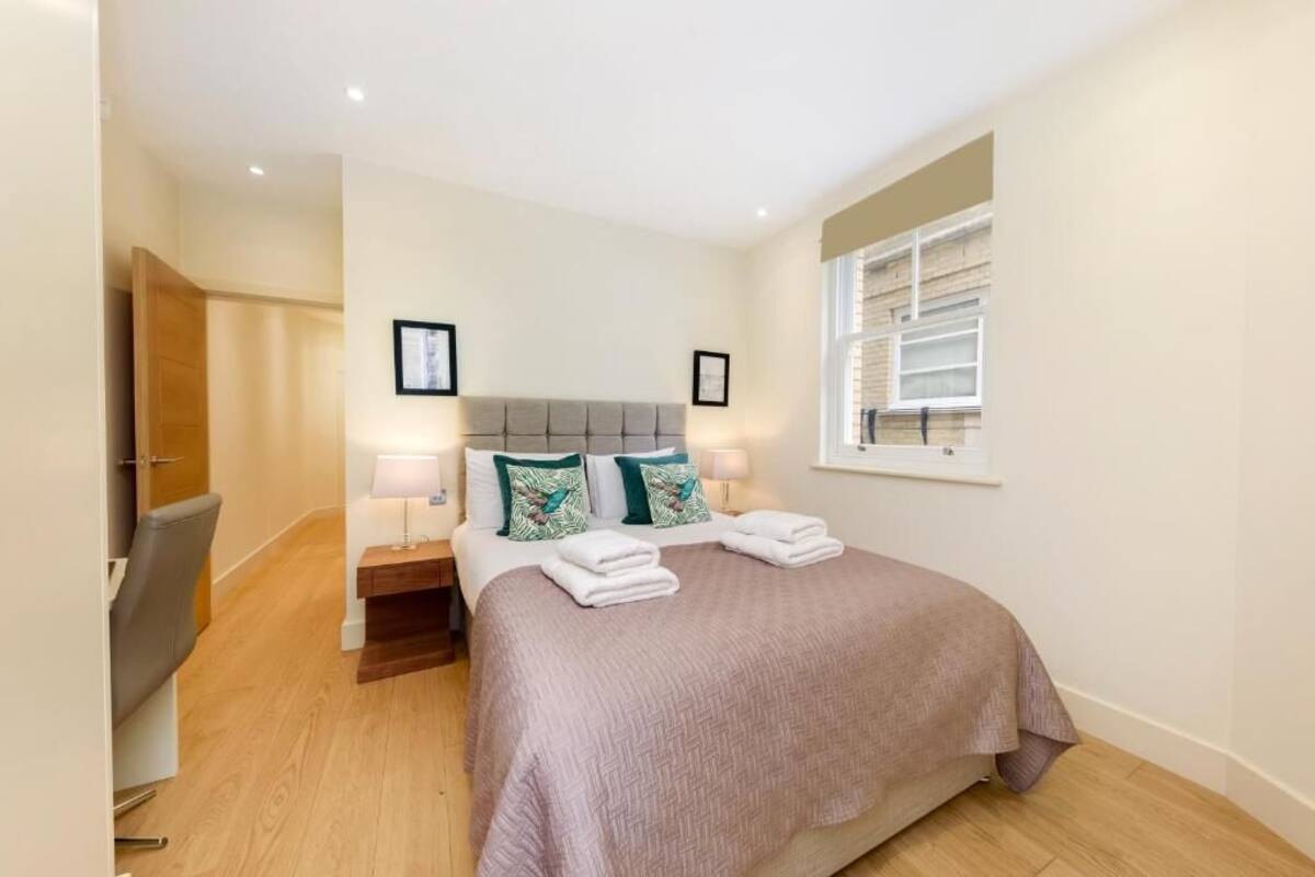 Une chambre à coucher avec un lit, des tables de chevet, une chaise, une fenêtre et une porte.