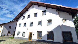 Un bâtiment blanc avec de nombreuses fenêtres, une porte en bois et une petite fenêtre ronde sur le côté.