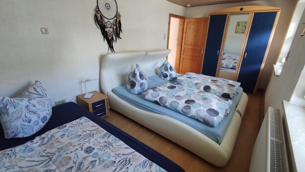 Une chambre à coucher avec un lit, des tables de chevet, une armoire et un miroir.