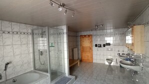 Une salle de bain moderne dotée d’une douche à parois de verre, d’une baignoire, de toilettes et d’un lavabo.