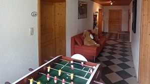 Une pièce avec une table de baby-foot, un canapé et un sol à carreaux.