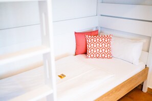 Rest on a plush bed with a comfortable headboard, featuring a stylish pillow arrangement and a convenient bedside storage.