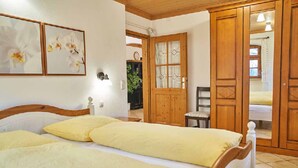 A bedroom with two beds, wooden wardrobe, and a small table.