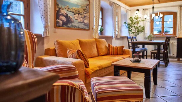 A cozy living room with a sofa, striped armchairs, a wooden coffee table, and a painting on the wall.