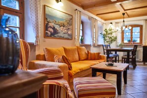 A cozy living room with a sofa, striped armchairs, a wooden coffee table, and a painting on the wall. - Ferienpension Posthof (Waldmuenchen)