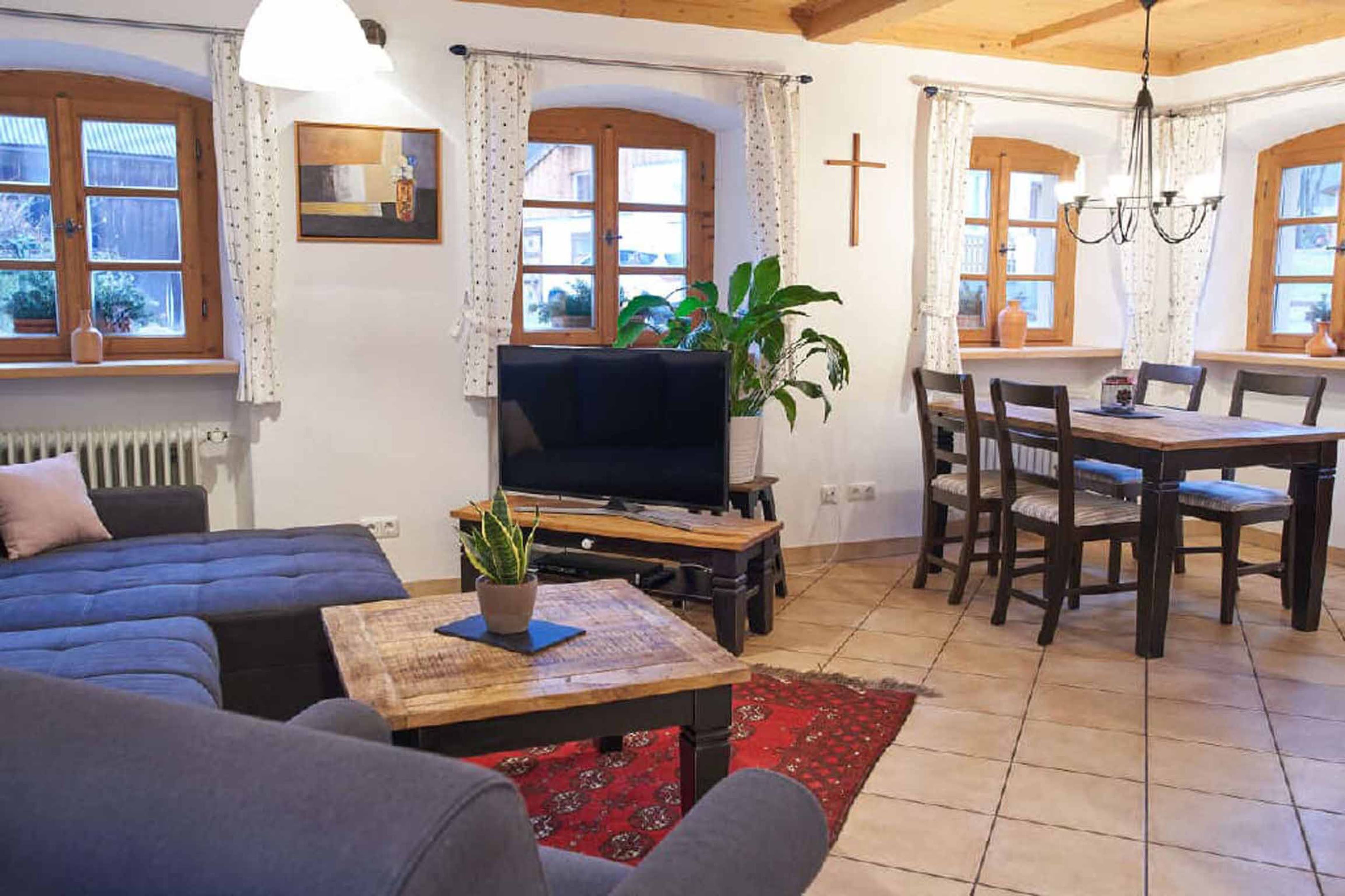 Una sala de estar acogedora con un sofá, televisor, mesa de centro de madera y un comedor con sillas y mesa.