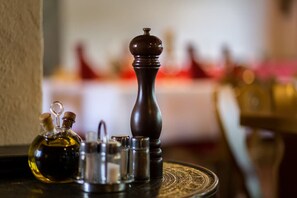 A salt and pepper shaker set on a round table with a bottle of oil and other condiments. - Pension Lutter (Bodenwoehr)
