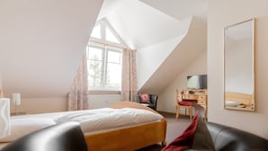 A bedroom with a bed, a desk, a chair, a TV, and a large window. - Pension Lutter (Bodenwoehr)