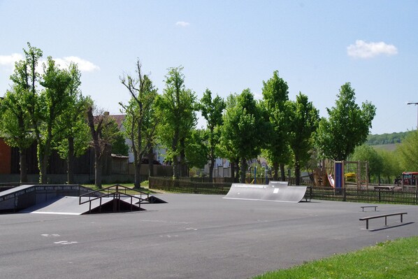 An outdoor skate park with ramps and a fenced area.