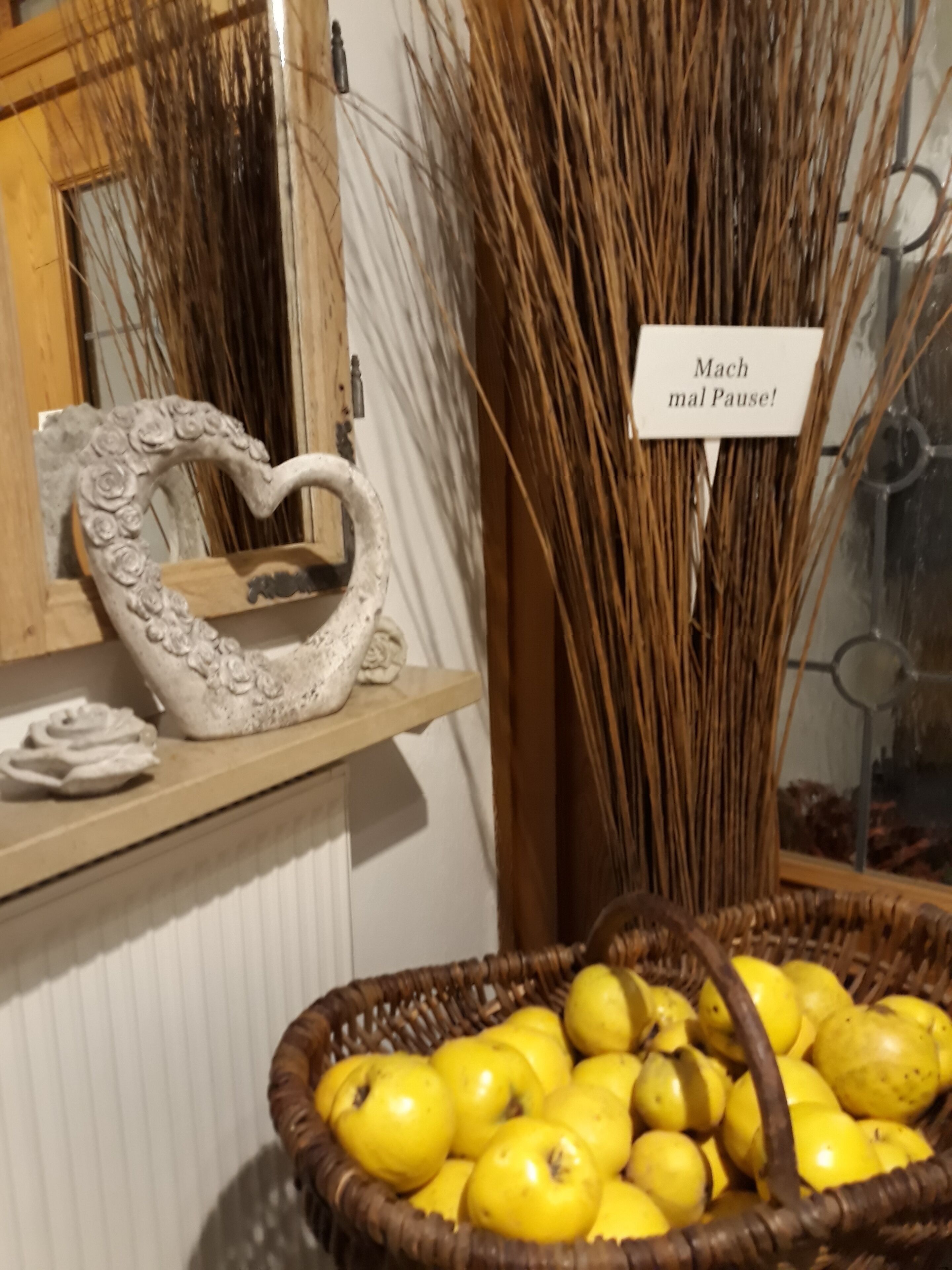 Un objet décoratif en forme de cœur posé sur une étagère, un panier de fruits jaunes et une enseigne avec du texte.