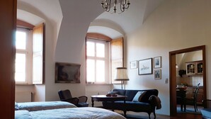 Un dormitorio con dos camas, un sofá, una mesa de comedor y una cocina visible a través de un arco.