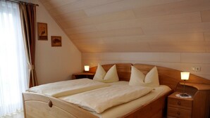 Una cama doble con dos mesitas de noche, un cabecero de madera y una pequeña mesilla con una lámpara.