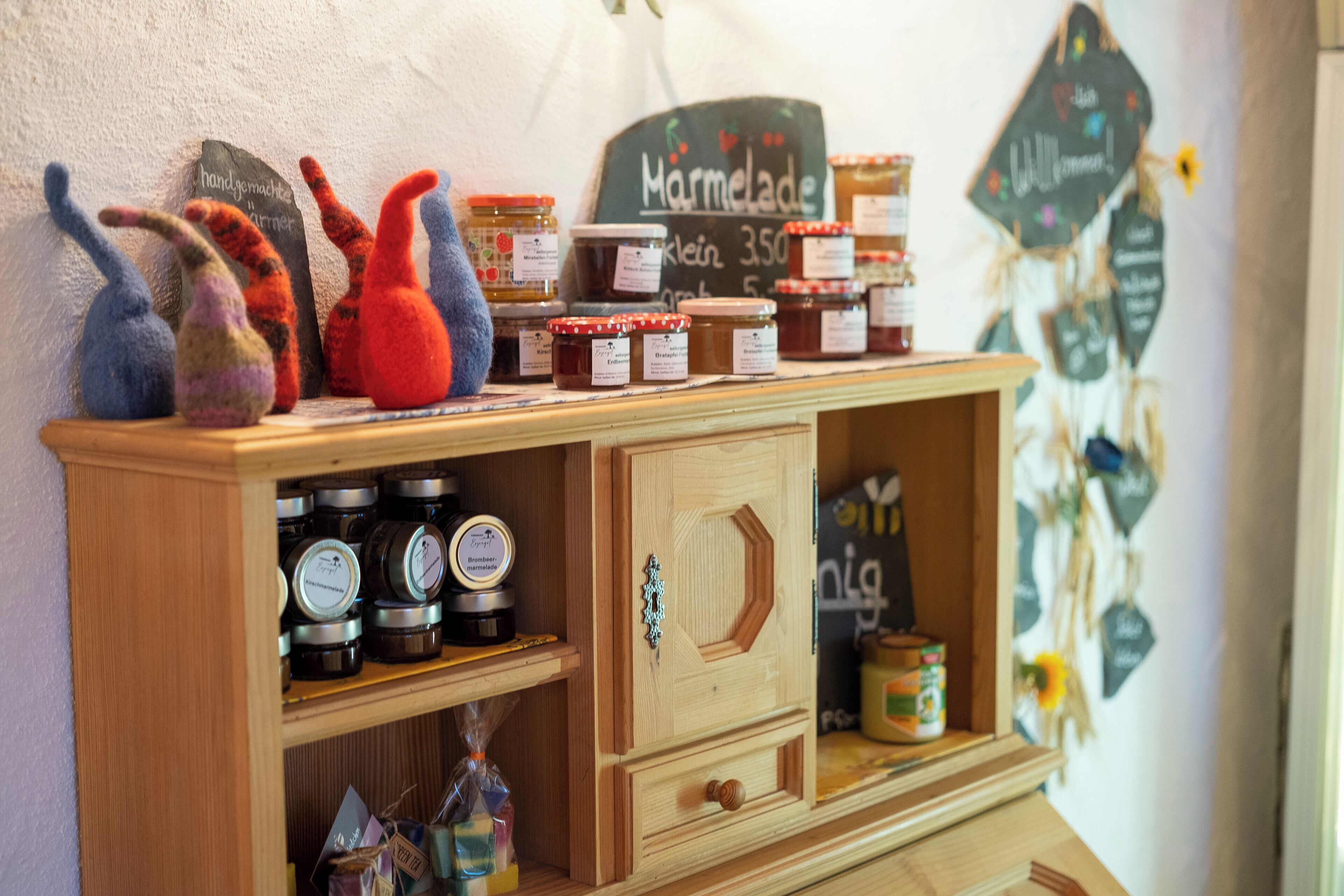 Una vetrina in legno con barattoli di marmellata e miele, e decorazioni di animali imbottiti sopra.