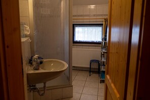 A bathroom with a sink, a shower, a window, and a radiator. - Bio Ferienhof Erzengel (Berg)