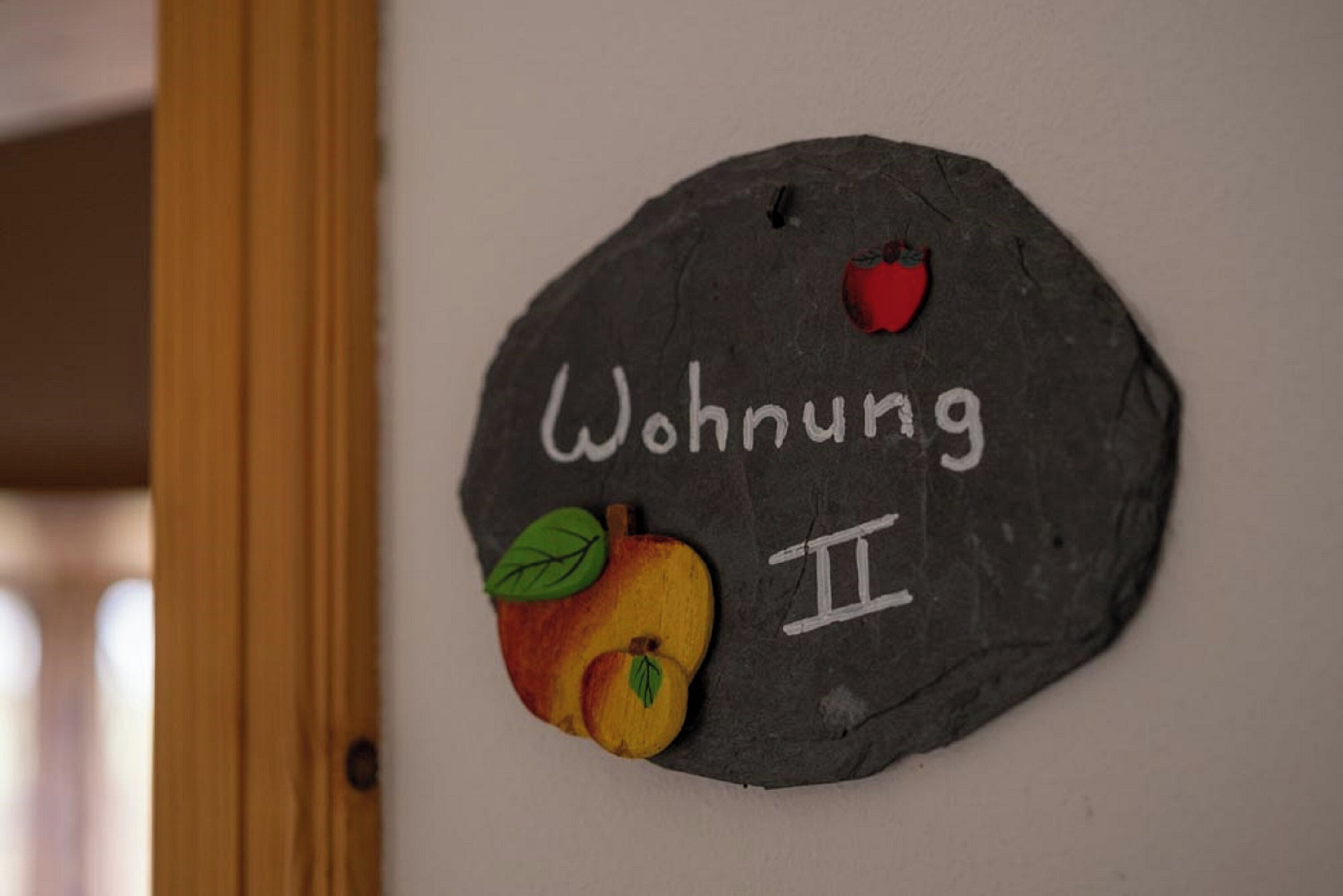 A stone wall with the text "Wohnung II" and a painted apple.