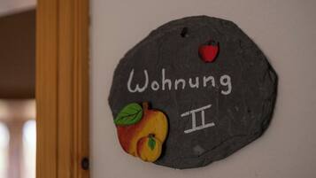 A stone wall with the text "Wohnung II" and a painted apple.
