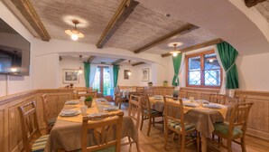 A dining area with wooden tables and chairs, a wooden ceiling, and a window with curtains. - Chalet Murr by Skinetworks (Sankt Anton am Arlberg)