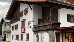 A traditional chalet-style building with a stone foundation, wooden balconies, and multiple windows with shutters. - Chalet Murr by Skinetworks (Sankt Anton am Arlberg)